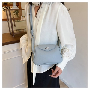 Close-up of light blue pebble leather crossbody bag with silver twist lock and strap