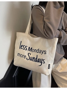 Large off-white canvas tote bag with 'less Mondays more Sundays' text in shoulder carry view