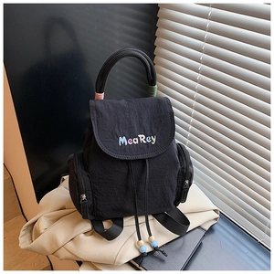 Detail of a black mini backpack with a colorful brand logo, drawstring, and side zippers