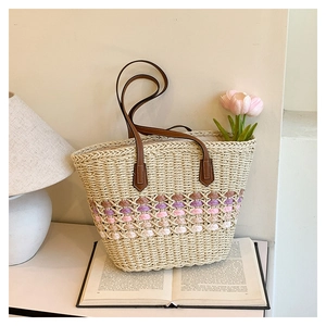 Détail du sac cabas en paille tissé à la main avec motifs colorés et anses en cuir brun