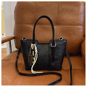 Détails de la texture tissée du sac noir avec un pendentif en forme de chocolat