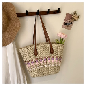 Détail d'un sac cabas en paille avec motifs à vagues colorés sur un crochet en bois