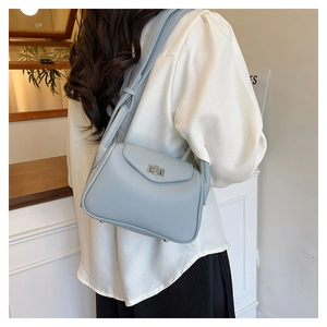 Detail of light blue lychee pattern leather handbag with silver twist lock on female model