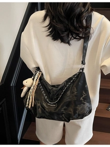 Grand sac cabas noir en PU effet marbre avec charm ours et chaîne porté par un modèle