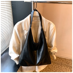 Detail of premium black PU leather tote bag hanging against a minimal office backdrop