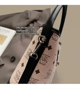 Close-up of pink pebbled leather handbag featuring premium silver hardware and bear print