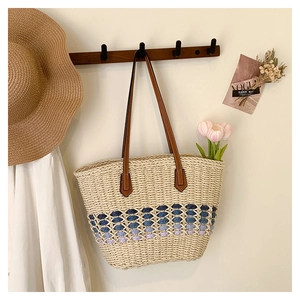 Détail du sac cabas en paille avec motifs tressés dégradés bleus et anses en cuir marron
