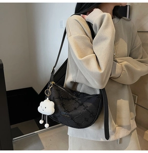 Detail of black pleated crescent bag with sequin texture and plush cloud charm accent