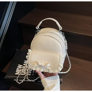 Detail of cream mini backpack with delicate lace trim and a sweet bow decoration