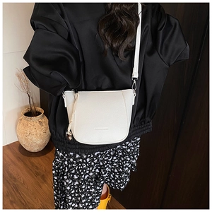 Détail du sac seau en cuir blanc avec pompon tressé et logo de mode sur le devant