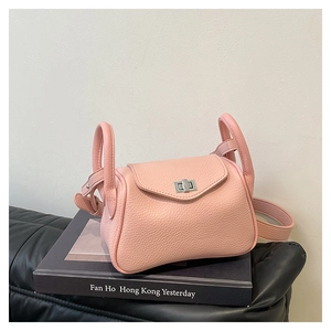 Detail view of pink lychee leather handbag featuring silver metal hardware on a book