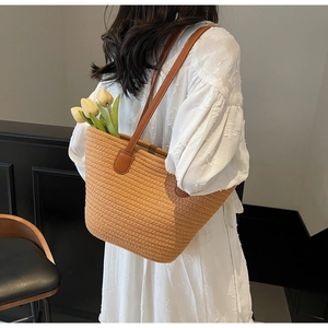 Detail of woven straw tote bag with brown faux leather straps and stripe texture