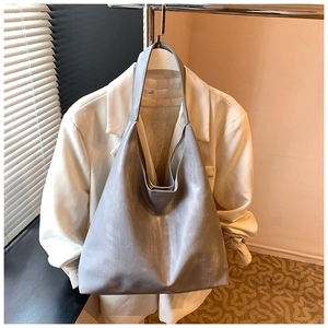 Detail of vintage gray faux leather tote bag with distressed texture on a hanger