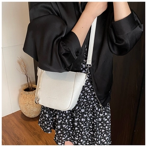 Détail du sac seau en cuir grainé blanc avec boucle argentée et pendentif à nœud