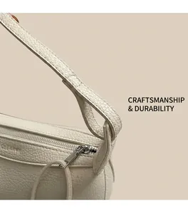 Close-up of litchi grain texture and neat stitching on a cream leather shoulder bag