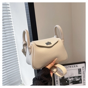 Detailed macro view of cream litchi grain leather bag with silver metal rotating lock