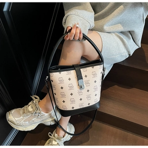 Detail showing the creamy white bucket bag with cartoon bear print and silver metal lock
