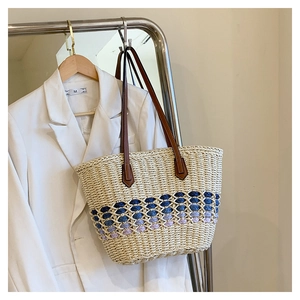 Détail de la texture en paille tressée avec bande dégradée sur un grand sac de plage
