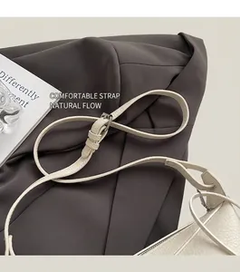 Close-up of adjustable strap with silver buckle on lychee textured cream shoulder bag