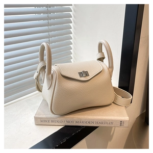 Detail of cream white pebbled leather shoulder bag with silver twist lock on art books