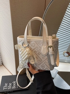 Beige floral jacquard bucket bag with pearl heart charm and adjustable shoulder strap