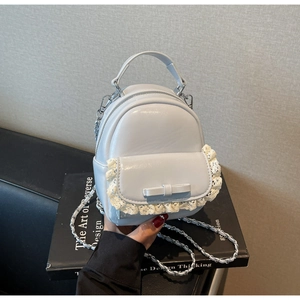 Detail of light blue PU leather backpack with lace trim and bow accent on front pocket