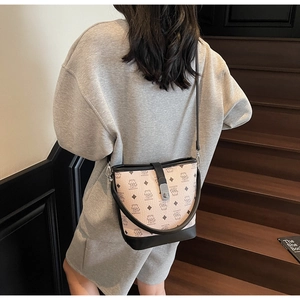 Detail view of beige bucket bag with black trim and bear pattern on a dark staircase