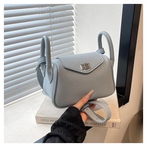 Detail of light blue lychee pattern leather handbag with silver metallic turn-lock closure