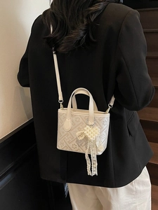 White geometric pattern bucket bag with pearl heart charm and crossbody strap