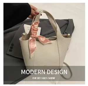 Close-up of cream lychee leather bucket bag featuring a pink heart silk scarf on handle