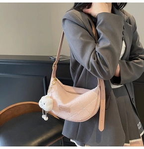 Close-up of pink half-moon bag featuring embossed texture and white cloud plush charm