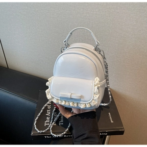 Detail of light blue leather mini backpack with lace trim, bow, and silver chain strap