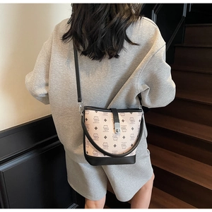 Detail view of the beige bucket bag with bear patterns on a dark wooden staircase