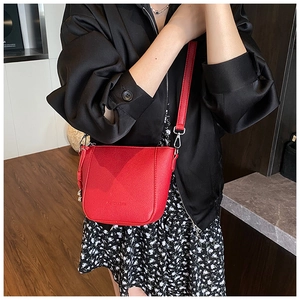 Détail du sac bandoulière en cuir grainé rouge avec boucles métalliques argentées