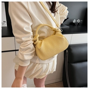 Detail of yellow pleated handbag with vertical ruffles and detachable crossbody strap