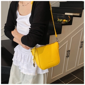 Détail d'un sac seau jaune en cuir grainé avec une bandoulière au design minimaliste