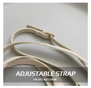 Close-up of white lychee leather adjustable shoulder strap with golden metal buckle