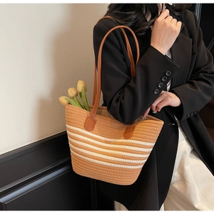 Detailed view of striped woven tote bag with brown leather handles and large capacity