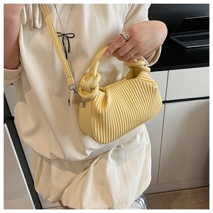 Close-up of soft yellow pleated faux leather handbag with round handle and metal hardware