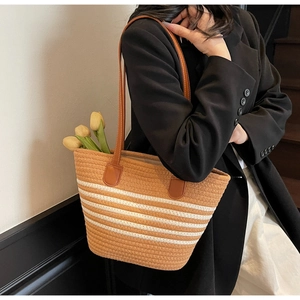 Detail of woven tote bag showing striped pattern texture and brown leather shoulder straps