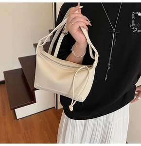 Detail of off-white lychee texture leather handbag with silver zipper and long puller