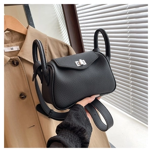 Detail of black litchi grain leather mini handbag with metal turn-lock and dual handles