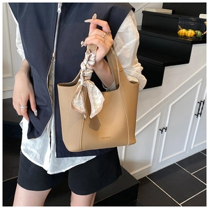 Detail of camel lychee leather bucket bag with HOCOMU logo and pink heart silk scarf