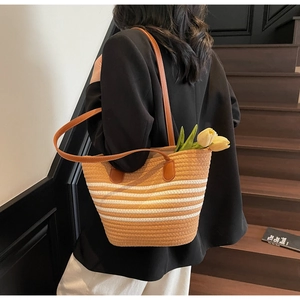 Close-up of brown and white striped woven tote bag with leather straps on a model