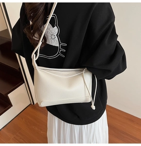 Detail shot of white lychee leather texture and knot decoration on the shoulder bag