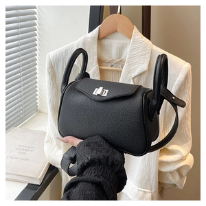 Detail of black pebbled leather handbag featuring silver twist lock and dual handles