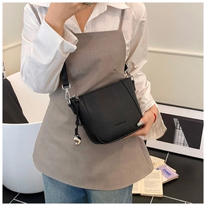 Détail du sac seau noir en cuir grainé avec breloque cœur argentée et bandoulière