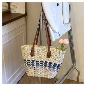 Détails du sac cabas en paille avec motifs bleus et poignée en cuir marron chic