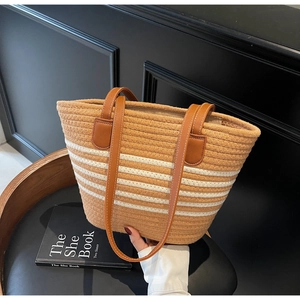 Detail of woven beach tote with brown and white stripes and faux leather shoulder straps
