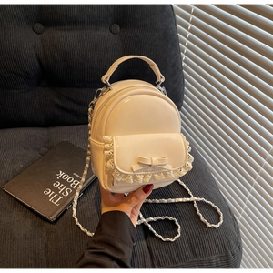 Chic cream mini backpack featuring lace trim, bow detail, and a metallic chain strap